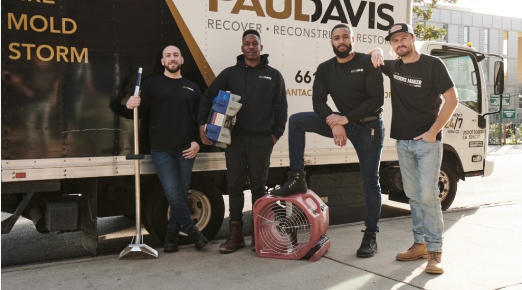 Paul Davis Restoration of Livonia/Farmington MI restoration team standing beside emergency response truck with water damage drying equipment and cleanup tools ready for 24/7 disaster restoration service